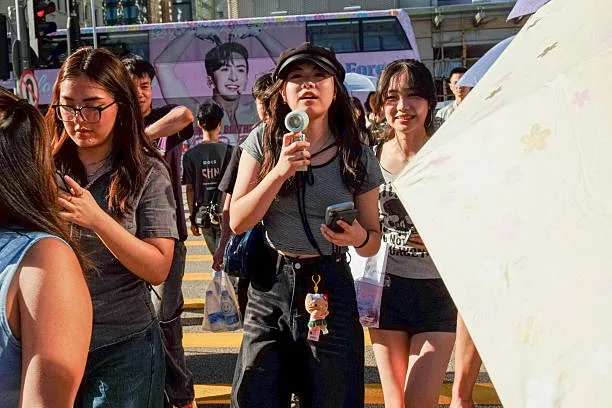 香港一名女孩在強烈的陽光下使用便攜式風扇為臉部降溫。（Sawayasu Tsuji/Getty Images）