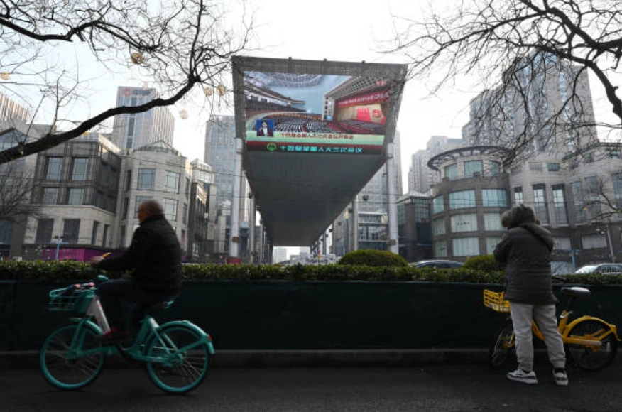 一名男子騎著自行車經過北京人民大會堂。 (Photo by GREG BAKER / AFP) (Photo by GREG BAKER/AFP via Getty Images)