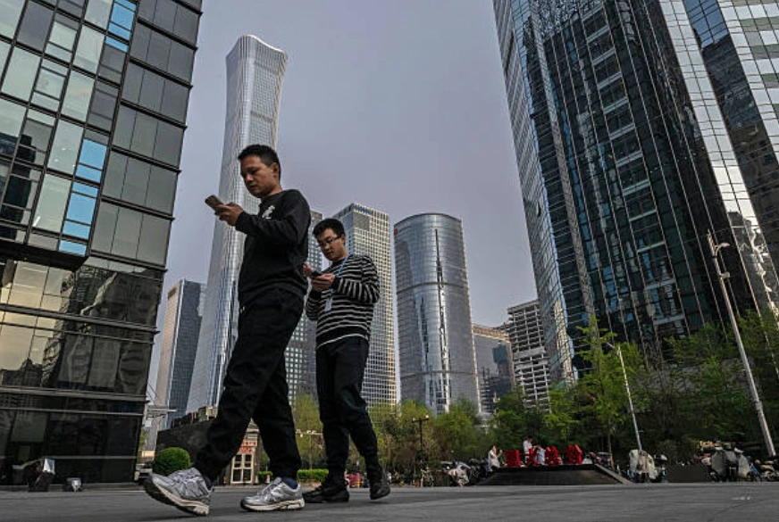 示意图：北京中央商务区的一栋办公大楼内，上班族们一边低头看手机一边返回大楼。 (Photo by Kevin Frayer/Getty Images)