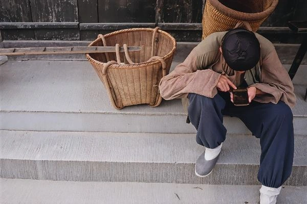 中国东部浙江省东阳市横店影视城，在拍摄一部电视剧的间隙，一名身着古装的群众演员正在看手机。(MATTHEW KNIGHT/AFP via Getty Images)