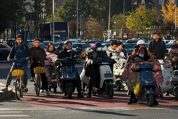 上海的電動自行車銷售門店近期出現大規模集體關門現象。圖為騎乘電動自行車和滑板車的人們在等候紅綠燈。（Cheng Xin/Getty Images）