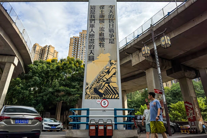 遊客走過位於中國重慶一處昔日戰爭遺址的抗日標語和圖案柱。 (Photo by Cheng Xin/Getty Images)