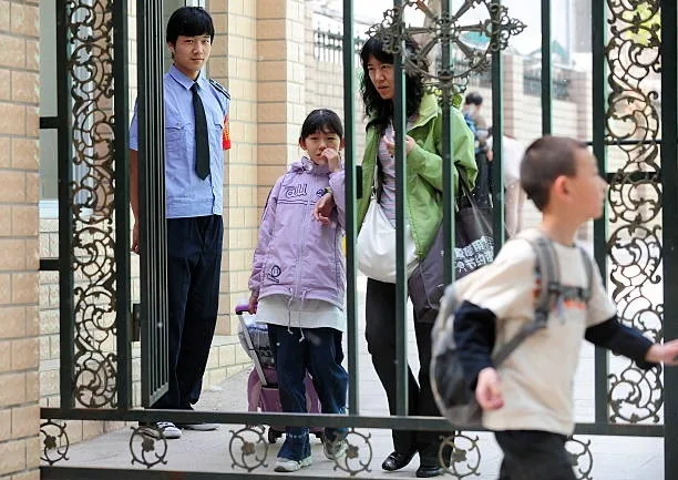 北京一所小學放學時，家長們正在接孩子，保安人員在校門口出入口處把守。資料圖片。（FREDERIC J. BROWN/AFP via Getty Images）