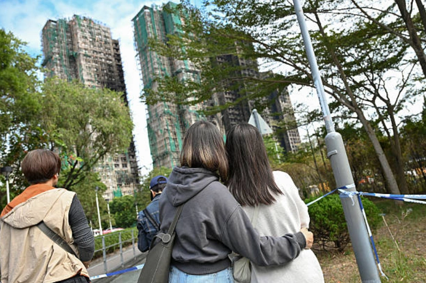 2025年12月1日，在香港大埔区发生11月26日致命火灾后，人们抬头望向王福苑公寓楼。 (Photo by Peter PARKS / AFP via Getty Images)