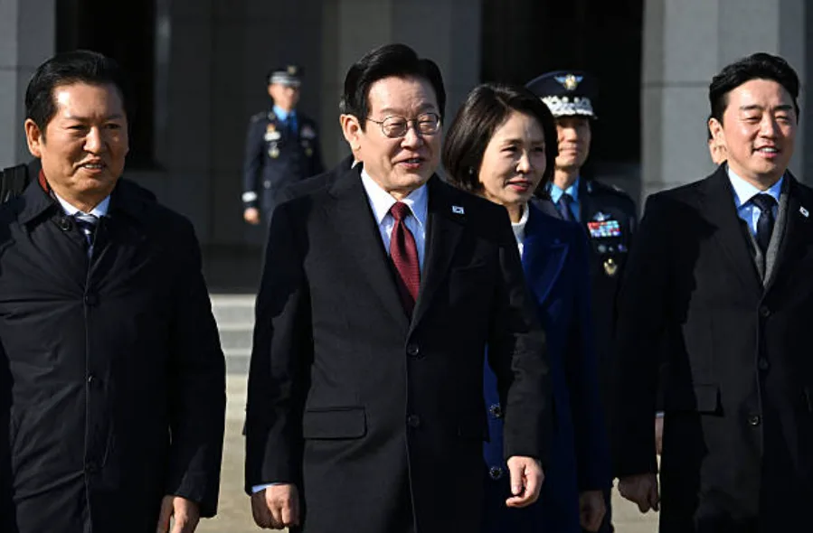 2026年1月4日，韩国总统李在明（中）和夫人金喜京（右二）在首尔城南空军基地走向飞往中国的飞机。 (Photo by Jung Yeon-je / AFP via Getty Images)