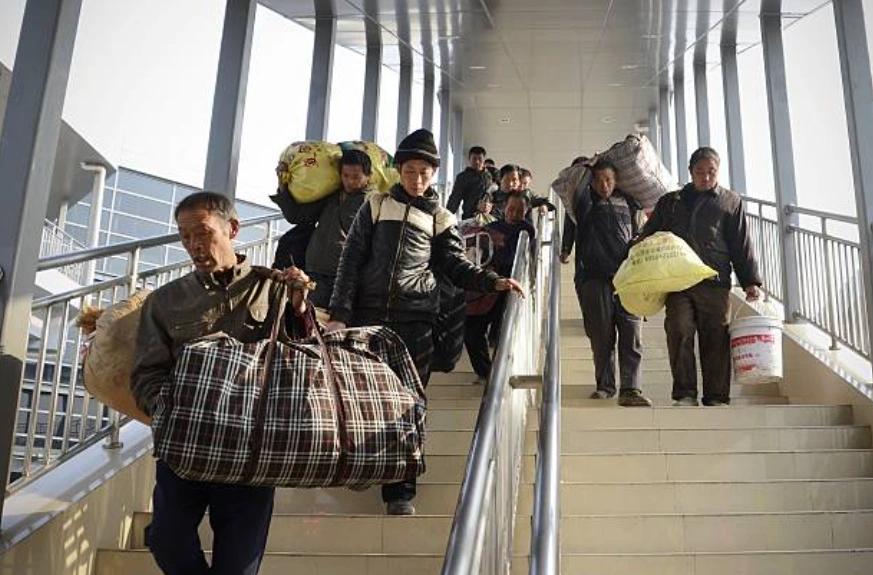 一群農民工提著行李走下北京一個汽車站的樓梯。(Photo credit should read WANG ZHAO/AFP via Getty Images)