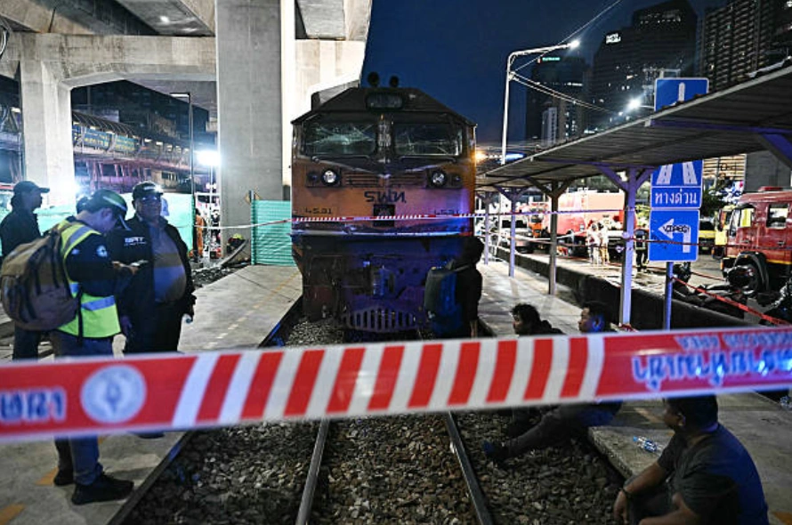 2026年5月16日，在曼谷瑪卡山機場輕軌站下方，一列貨運列車與一輛巴士相撞，事故造成至少8人死亡，30多人受傷。圖為事故現場附近，工作人員站在事故現場。(Photo by Lillian SUWANRUMPHA / AFP via Getty Images)